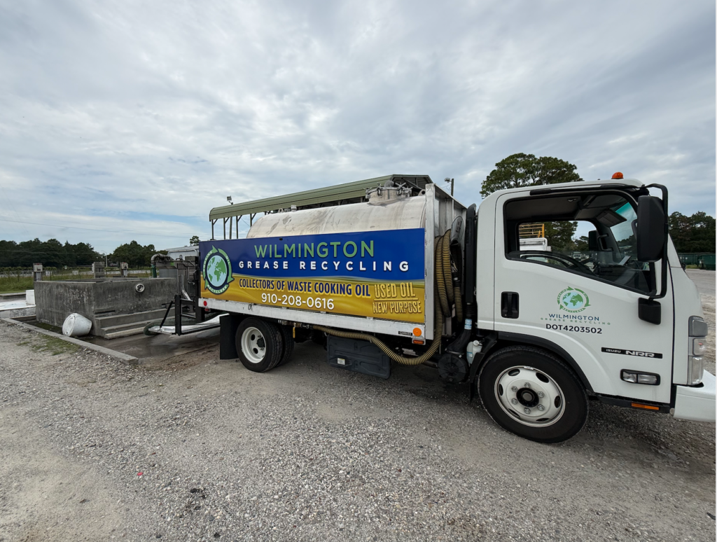 Wilmington Grease Recycling truck parked at a commercial facility near an outdoor waste collection area.